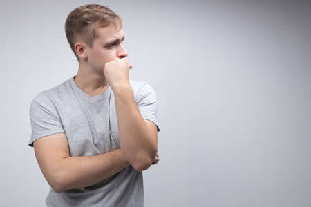 Portrait of a pensive handsome man looking away at copy space with hand on her chin isolated over white backgroundの写真素材
