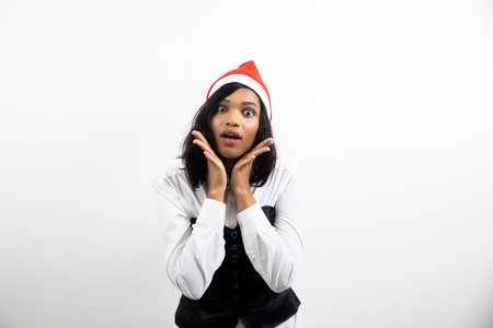 Close-up photo of a pretty cute African surprised excited positive girl in a Santa Claus hat isolated white background.の写真素材