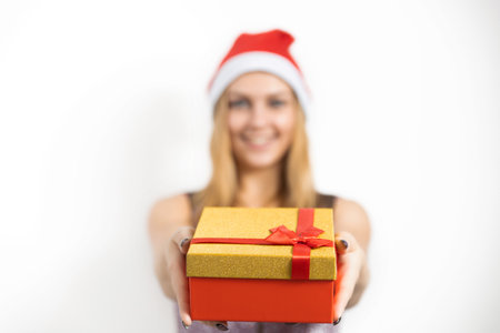 A glamorous young woman holds a Christmas present in her hands. A wonderful female model is preparing for a new year's partyの写真素材