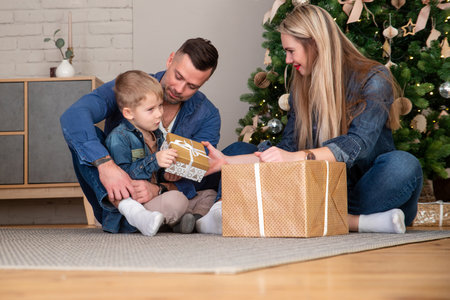 Merry Christmas and happy holidays mom, dad and son sort out gifts. A loving family enjoys the New Year's moodの写真素材