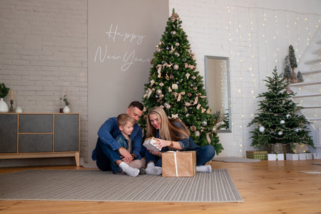 Merry Christmas and happy holidays mom, dad and son sort out gifts. A loving family enjoys the New Year's moodの写真素材