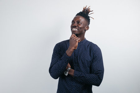 A picture of an attractive young black man dressed casually, looking up with a thoughtful...