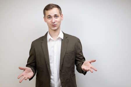 Handsome male businessman spread his hands to the sides gesturing during discussion on gray background with copy spaceの写真素材
