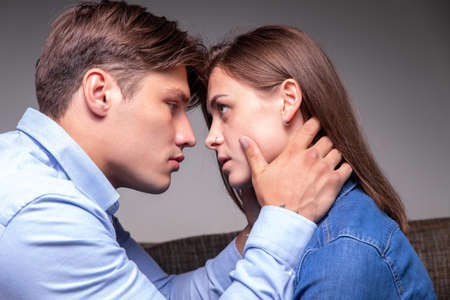 Affectionate handsome man hugging young girl on neck, begging her pardon, couple in love enjoying moment of closenessの写真素材