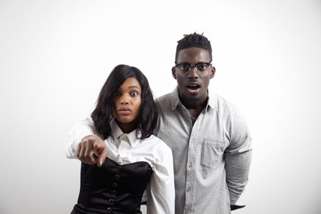 Surprised african american man and woman on white studio background point to camera showing their choiceの写真素材