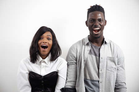 Amazed excited positive african american couple looking at camera with opened mouths on white studio backgroundの写真素材