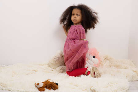 Portrait images of a 3-year-old African girl standing on a light blanket on the floor with a face depicting anger and resentment, a concept for Children with emotional expressions.の写真素材