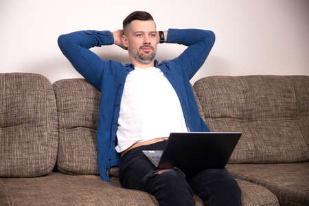 Relaxed satisfied businessman with laptop hold hands behind head think dream of future success. Positive thoughtsの写真素材