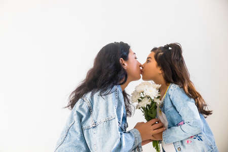 Happy young mother getting flowers from daughter little girl kid during mothers day. Tender moment of motherhoodの写真素材