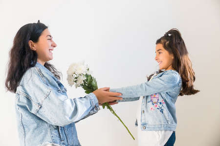 Happy young mother getting flowers from daughter little girl kid during mothers day. Tender moment of motherhoodの写真素材