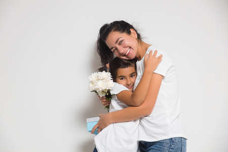 Cute child girl congratulating loving mum, giving bouquet of white flowers, gift box. Womens or Mothers Dayの写真素材