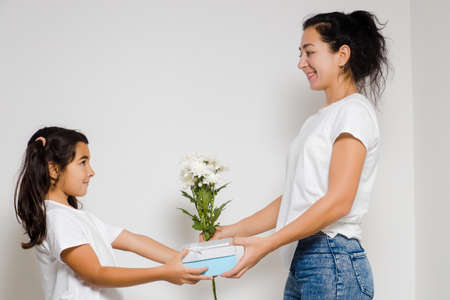 Girl child daughter hugging happy mom, congratulating with bouquet during Womens or Mothers Day. Copy space for adの写真素材