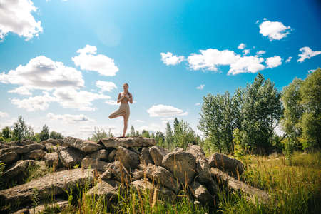Young girl doing yoga outdoor. Young woman practicing yoga in bamboo house, nature on background.Female happiness.Caucasian woman practicing yoga on vacation on Bali islandの写真素材