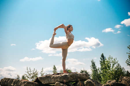 Young girl doing yoga outdoor. Young woman practicing yoga in bamboo house, nature on background.Female happiness.Caucasian woman practicing yoga on vacation on Bali islandの写真素材