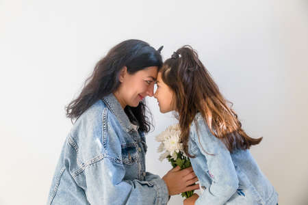Happy young mother getting flowers from daughter little girl kid during mothers day. Tender moment of motherhoodの写真素材