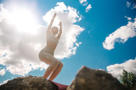 Yoga utkatasana chair pose by woman in silhouette with sunny sky background. Free space for textの写真素材