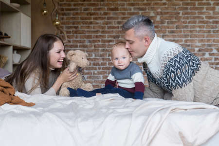 Affectionate young family having fun playing with little son on bed at home. Happy parenthood conceptの写真素材