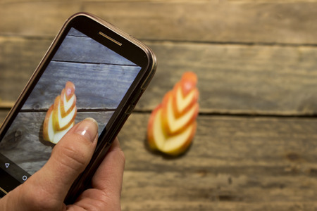 Girl takes a picture of a sliced apple .の写真素材