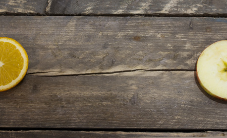 Fresh orange and apple  on a wooden table .