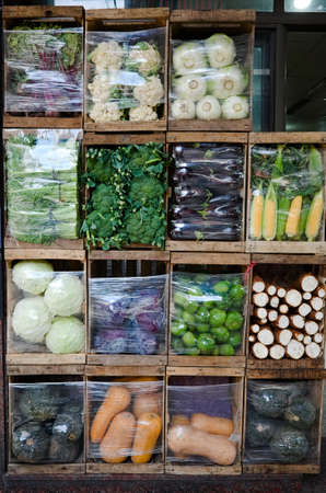 Street market vendor with vegetables packed in wooden boxes like cells to demonstrate variety of...
