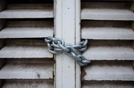 Metal chain hanging on closed entrance to the building close up.の写真素材