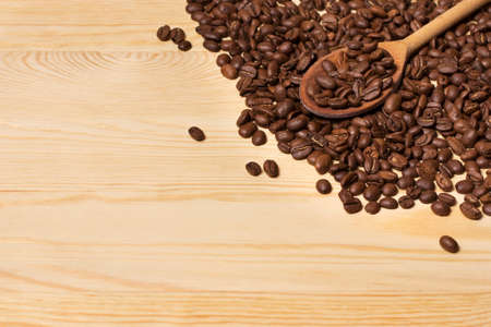 A wooden spoon lies on coffee beansの写真素材