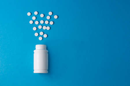 jar for pills with pills on a blue backgroundの写真素材