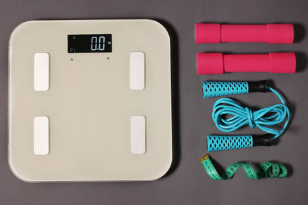 Scales, measuring tape, dumbbells, jump rope on a gray background. weight loss conceptの写真素材