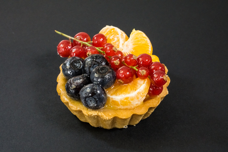 Cupcake with fresh bio fruits, orange, blueberry, red currant, side view photo, black background,shade from side light, dessert, snacks, pastries eco sweetsの写真素材