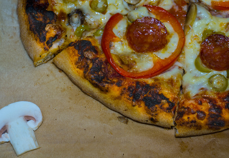 Italian pizza with pepperoni, mushrooms, mozzarella and tomato sauce. Pizza on the wooden table , In the frame is half pizza, and half fresh champignonの写真素材