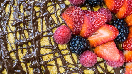 Sponge cake, chocolate on top, strawberries and raspberries, close-up, blackberry, top view, stone tableの写真素材