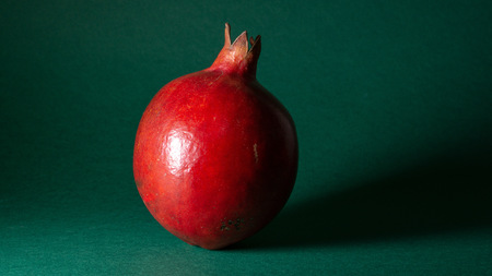 Bright juicy pomegranate fruit, green background, in the photo the fruit is located in the middle, close-upの写真素材