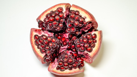 White background, top view, an open pomegranate is in the middle of the photo in which the grains of the fruit are visible.の写真素材