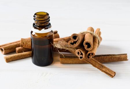 close-up, cinnamon sticks and cinnamon oil on a white wooden backgroundの写真素材