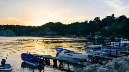 moored boats at the sea pier against the sunset sky