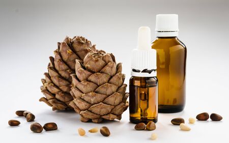 two pine cones with pine nuts and glass bottles on a white backgroundの写真素材