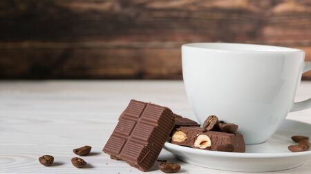 pieces of chocolate with hazelnuts and coffee beans on a brown tableclothの写真素材