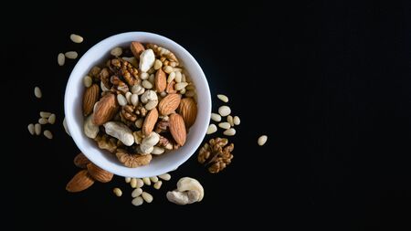 almond, cedar, walnuts, cashew nuts in a plate on a black backgroundの写真素材