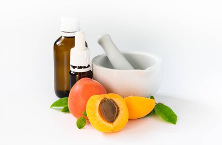 natural cosmetics concept, apricots with glass bottles with oil on, white backgroundの写真素材