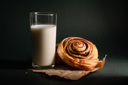 cinnamon roll and a glass of milk on a dark backgroundの写真素材