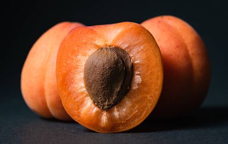 slice of ripe apricot with a seed on a dark background, close-upの写真素材