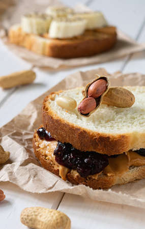 fast food, snack, two sandwiches with peanut butter jam and bananas on a white wooden table