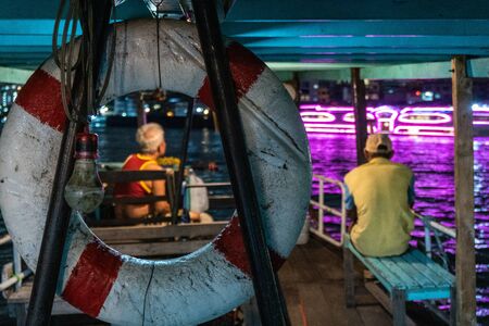Photo taken through a lifebuoy of a helmsman and his assistant on a small ferry, Bangkokの写真素材