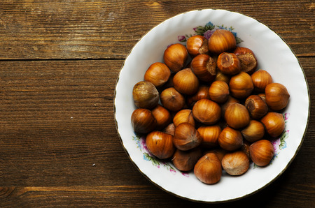 pile of hazelnuts in shell on wooden table .