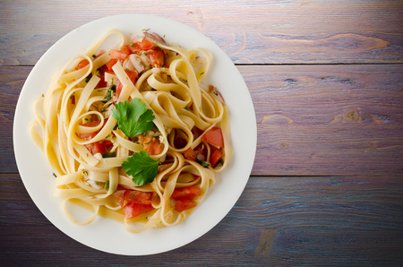 spaghetti on a plate. spaghetti tomatoes, onions, cabbage on a wooden backgroundの写真素材