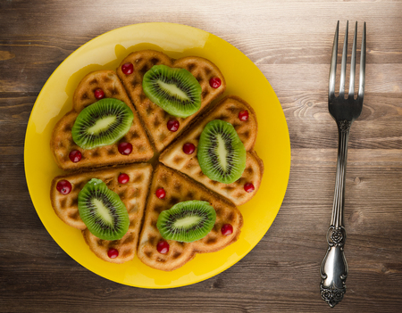 wafers with kiwi and cranberries on a wooden background. waffles on a plate top viewの写真素材