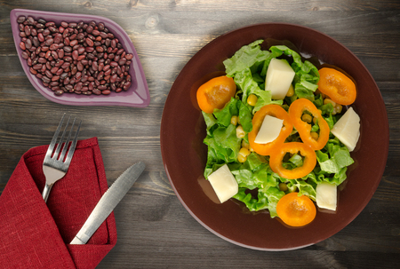  salad of cheese, lettuce, corn, pepper on a wooden background. Vegetarian salad on a plate. Vegetarian salad top viewの写真素材