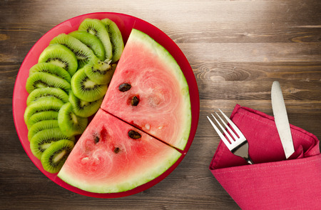 watermelon and kiwi sliced on a plate or a wooden backgroundの写真素材