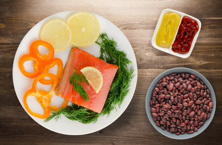 red fish trout fillets on a plate. fish trout on a wooden background. trout with dill, lemon and pepperの写真素材