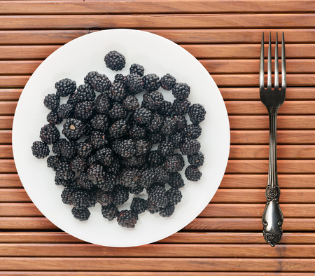 Blackberries on a plate on a wooden background. Vegetarian food. Healthy eating.の写真素材